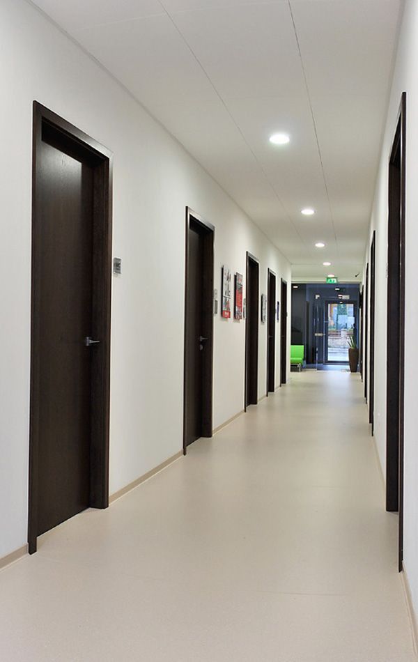 ممر داخلي بأرضية إيبوكسي لامعة بلون فاتح مع جدران بيضاء وأبواب خشبية داكنة وإضاءة سقفية بالمدينة المنورة