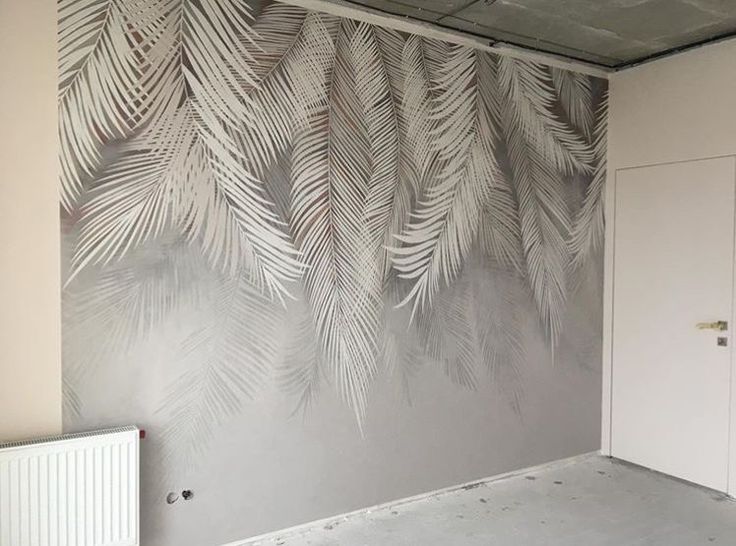 جدار داخلي بتصميم فني حديث مزخرف برسومات أوراق نخيل بيضاء متدرجة على خلفية رمادية ناعمة ضمن أعمال تشطيب وديكور منزل عصري
