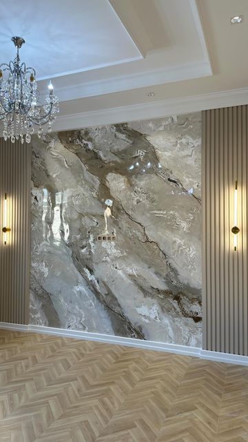 بديل رخام رمادي بالمدينة المنورة يحيط باللوح ألواح مضلعة وشرائح خشبية باللون البيج ويتدلى من السقف ثريا كريستالية