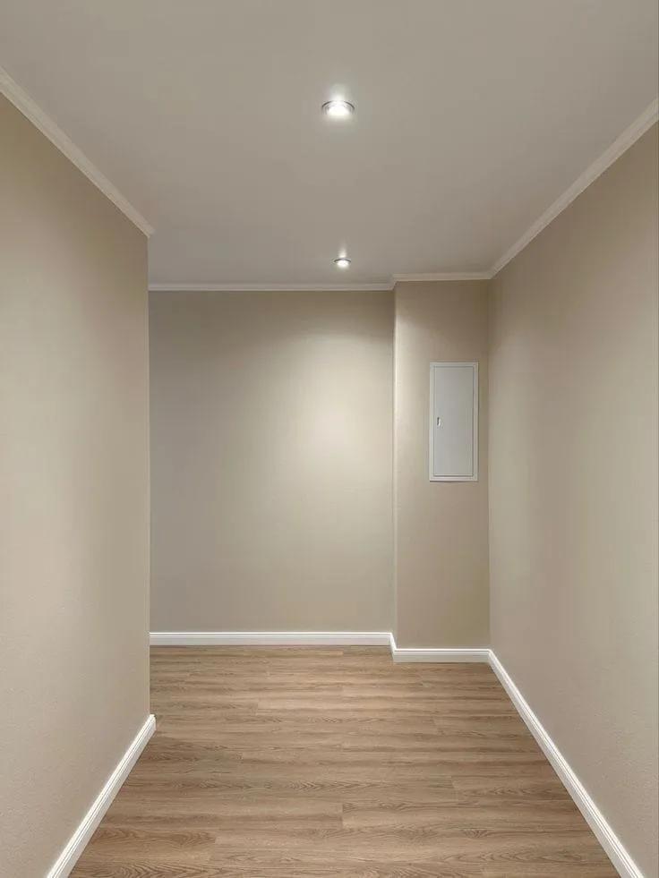 تنفيذ دهانات الممرات والمساحات الداخلية بألوان دافئة (البيج والرملي) في المدينة المنورة. (صورة لدهان موحد مع نعلات بيضاء)