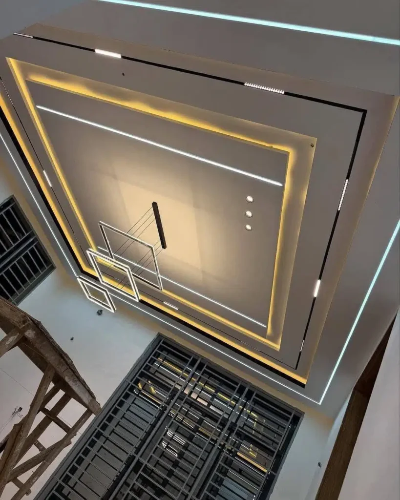 سقف جبس بورد بتصميم مربع ثلاثي الطبقات، باللون الأبيض وإضاءة مخفية صفراء دافئة، مع ثريا متدلية