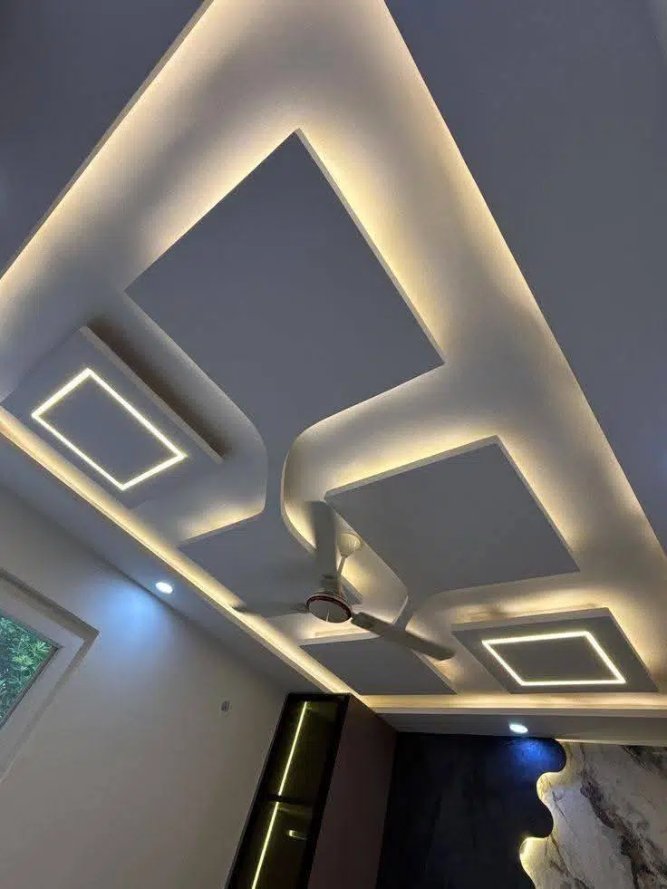 لسقف جبس بورد بأشكال وخطوط منحنية، مع إضاءة مخفية. يظهر التصميم مروحة سقف