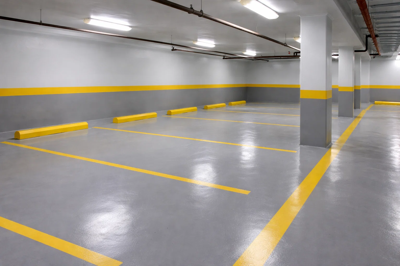 موقف سيارات داخلي مطلي بأرضية إيبوكسي رمادية لامعة مع خطوط صفراء لتحديد أماكن الوقوف،