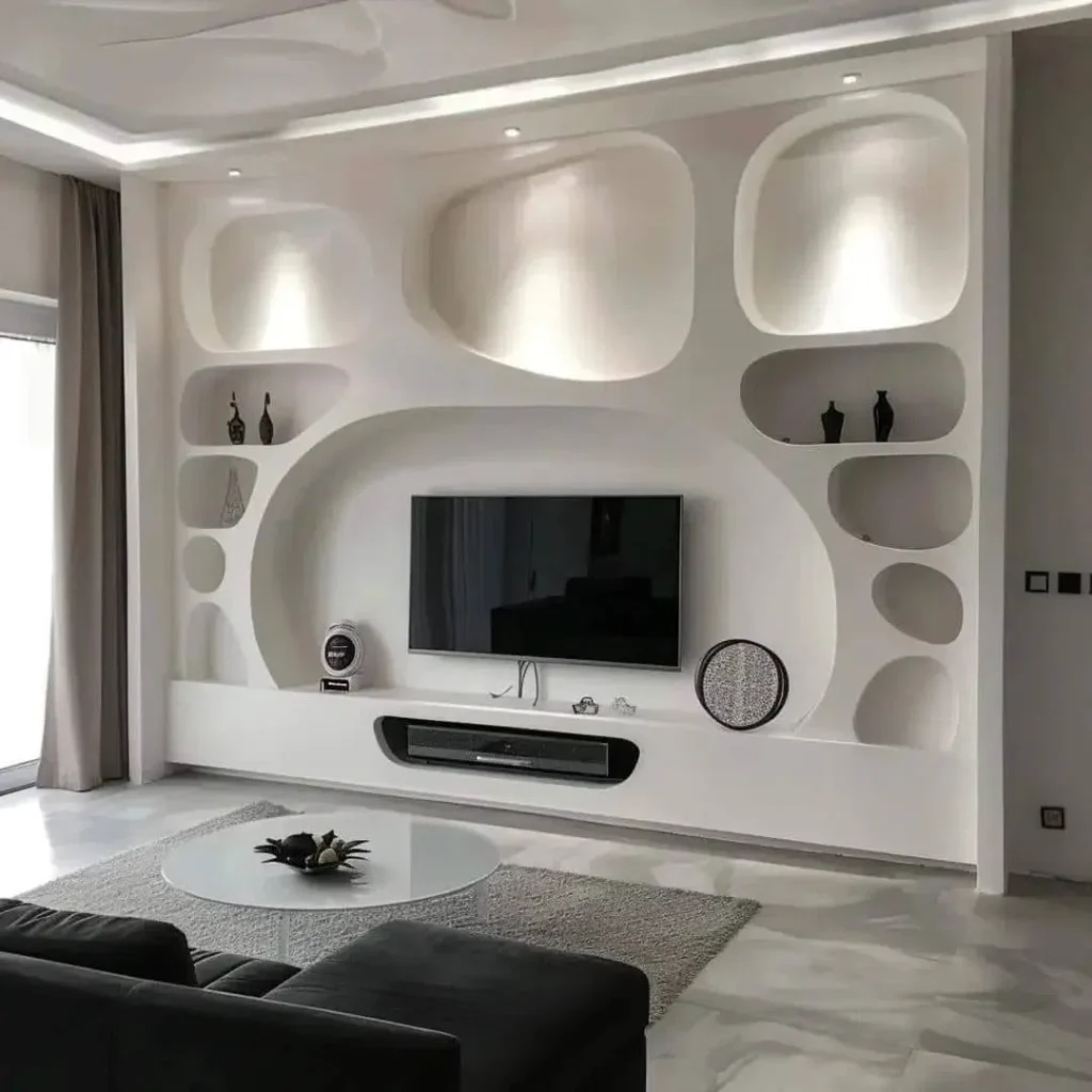 جدار تلفزيون جبس بورد مودرن باللون الأبيض، بتصميم يضم تجاويف ورفوف دائرية ومضيئة من ابداع معلم جبس بورد بالمدينة المنورة